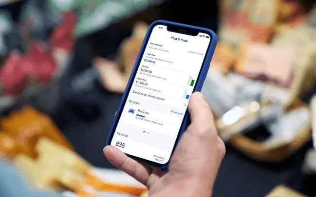 Hand håller en smartphone med en appvy för ekonomisk översikt